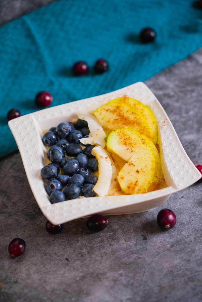 Ein Schüsselchen cremiges Porridge, belegt mit frischen Früchten, Nüssen und Honig, ideal für ein gesundes Frühstück.
