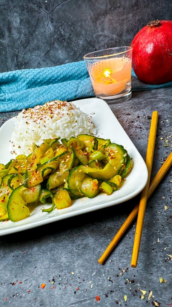 Eine Schale mit würzigem Gurkenkimchi, garniert mit Sesam und Frühlingszwiebeln.
