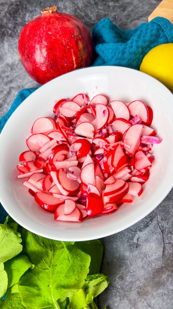 Eine Schüssel mit frischem Radieschensalat, garniert mit roten Zwiebeln und Zitronenscheiben, ideal für jede Mahlzeit.