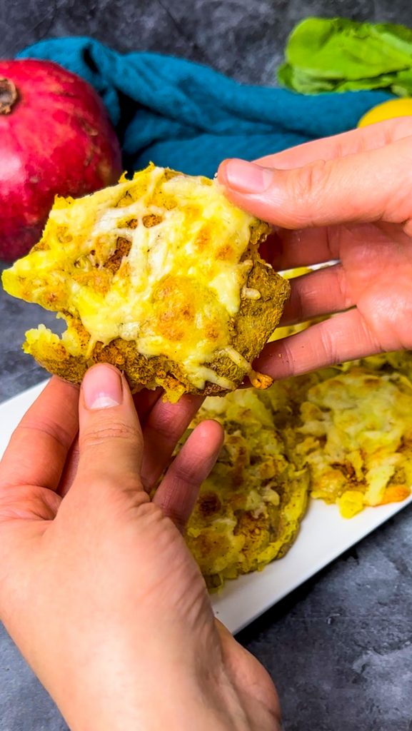 Goldbraune, knusprige Quetschkartoffeln mit geschmolzenem Käse, serviert mit cremigem Knoblauchdip.