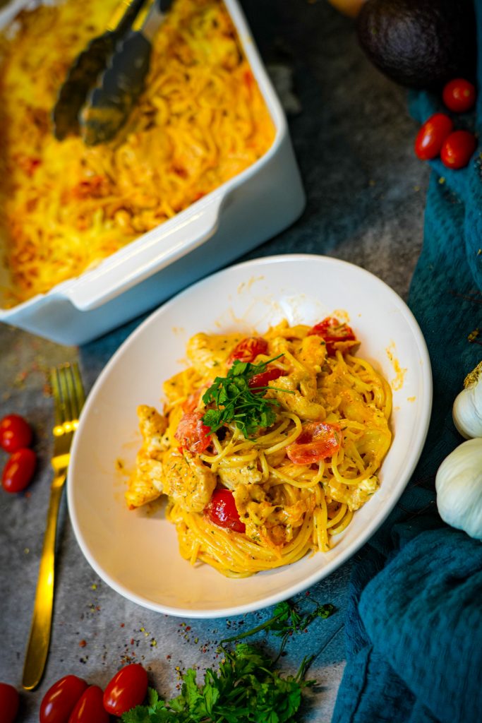 Cremige Gyrospasta mit Hähnchen, Cherrytomaten und überbackenem Käse in einer Auflaufform.