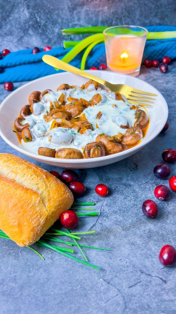 Pfannengerührte Champignons mit Zwiebeln und Knoblauch, serviert mit einer cremigen Knoblauchsoße und frischem Schnittlauch.
