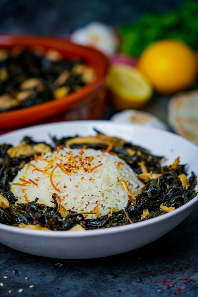 Mlokheye - Traditionelles arabisches Gericht mit Hähnchenfleisch und Mußkraut, serviert mit Reis und Zitronen.