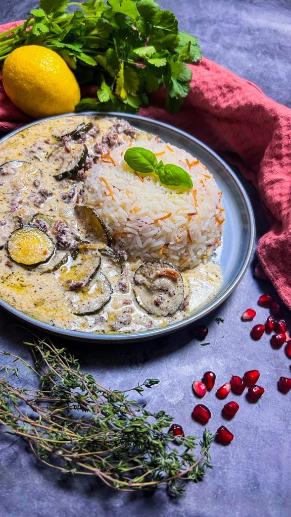 Arabisches Gericht mit Zucchini, Joghurtsoße und Reis, angerichtet mit Mandeln.