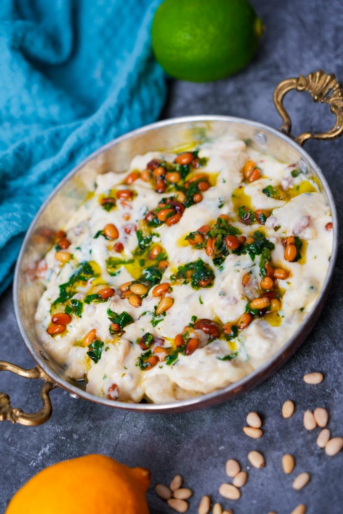 Arabische Shishbarak-Teigtaschen in cremiger Joghurtsuppe, garniert mit gerösteten Pinienkernen und frischem Koriander.