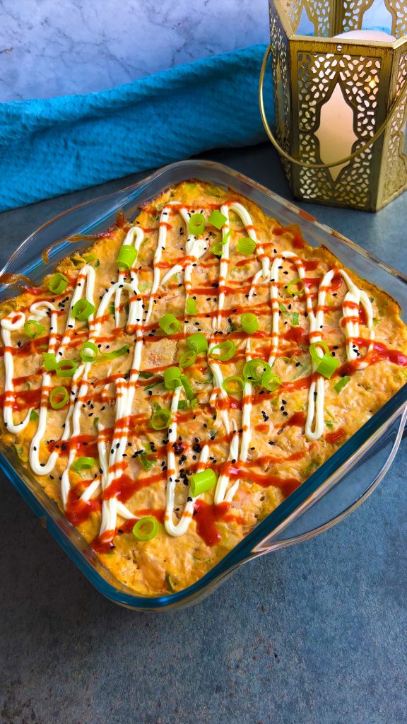 Sushi Bake aus dem Ofen, garniert mit Sriracha, Mayo und frischen Frühlingszwiebeln.