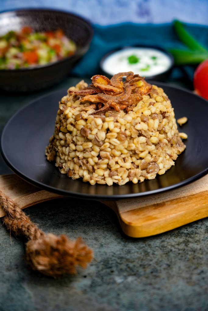 Mujaddara mit Bulgur: Herzhaftes Linsen-Bulgur-Gericht mit knusprigen Röstzwiebeln, serviert mit Joghurt und Salat.
